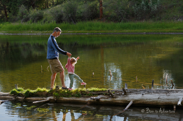 child walking the log with her dad